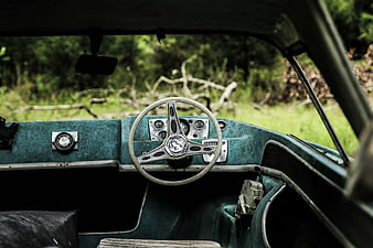 Vintage teal car interior with steering wheel and forest background