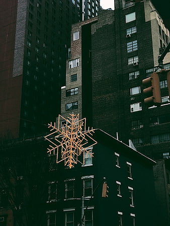 Illuminated Snowflake Decoration Against Dark Urban Buildings