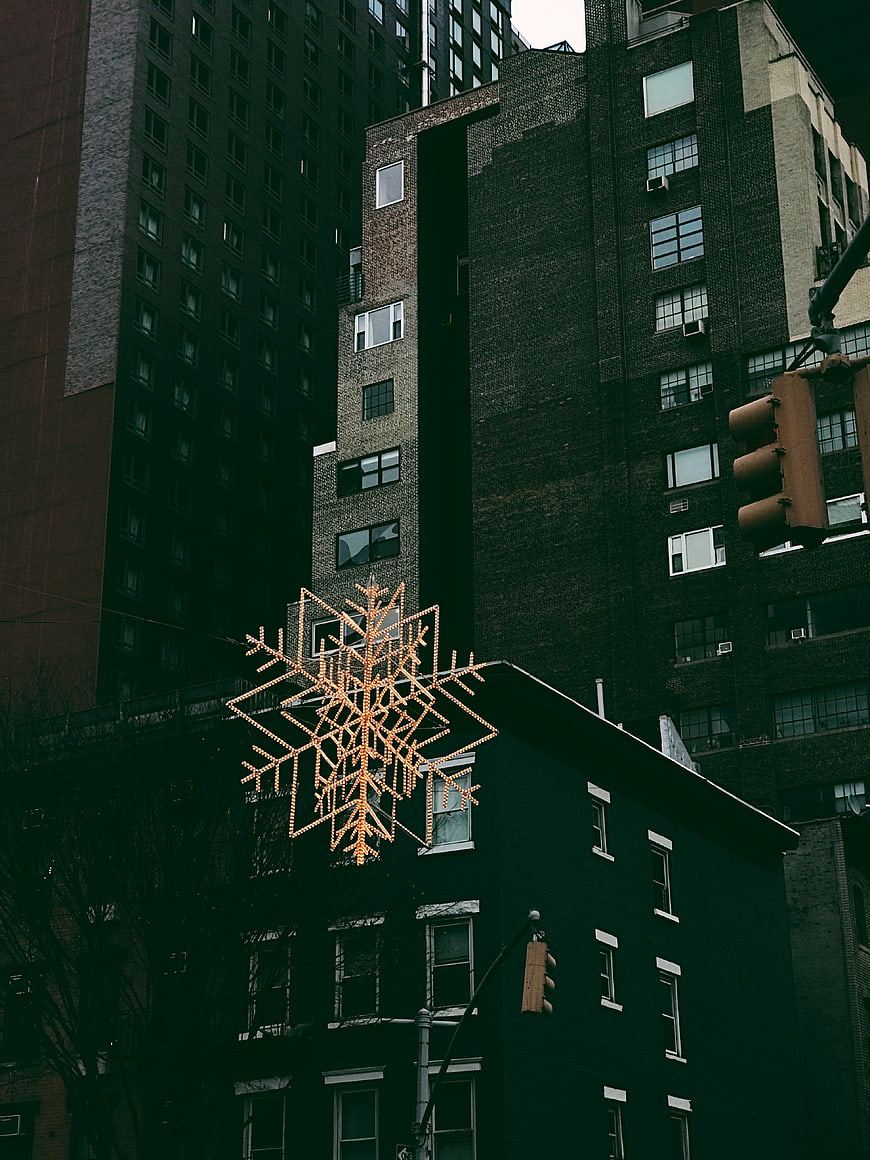 Illuminated Snowflake Decoration Against Dark Urban Buildings