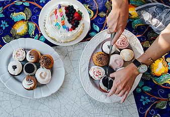 Overhead view of hands slicing cupcakes on white plates