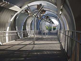 Modern architectural bridge with curved metal arches and wooden deck