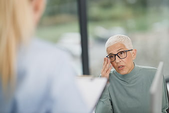 Senior woman with glasses consulting with doctor in clinic