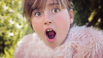 Close-up portrait of a surprised girl with wide eyes and open mouth