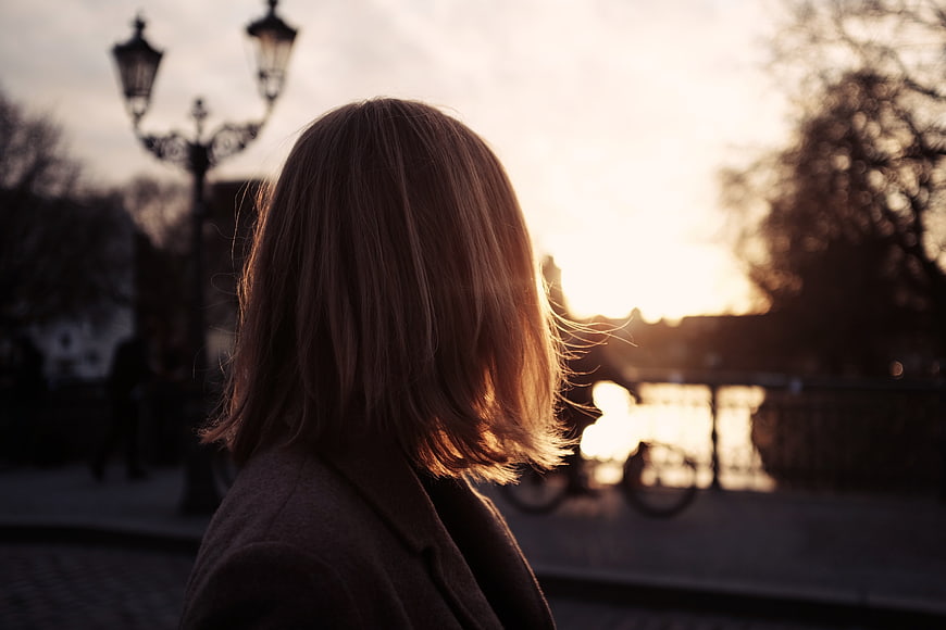 Woman with backlit hair looking at sunset in city