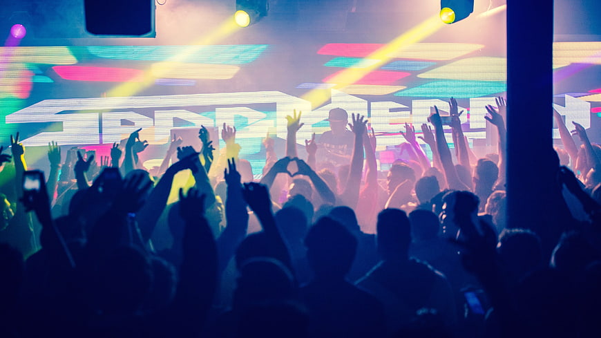 Energetic crowd at a vibrant nightclub concert with DJ
