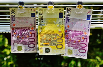 Euro banknotes hanging on a clothesline with smiley clips