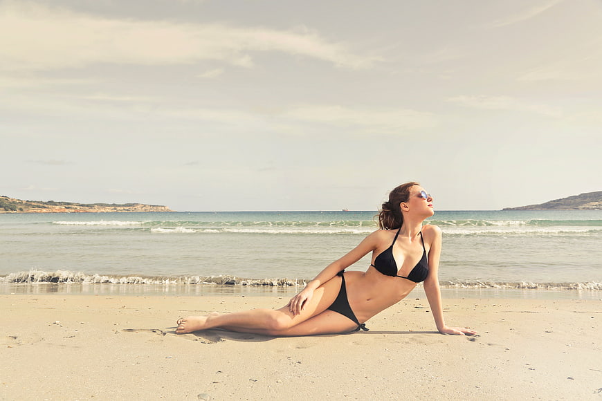 Woman in black bikini relaxing on sandy beach