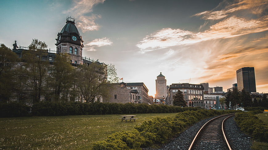 Train Tracks Leading to City Skyline at Sunset