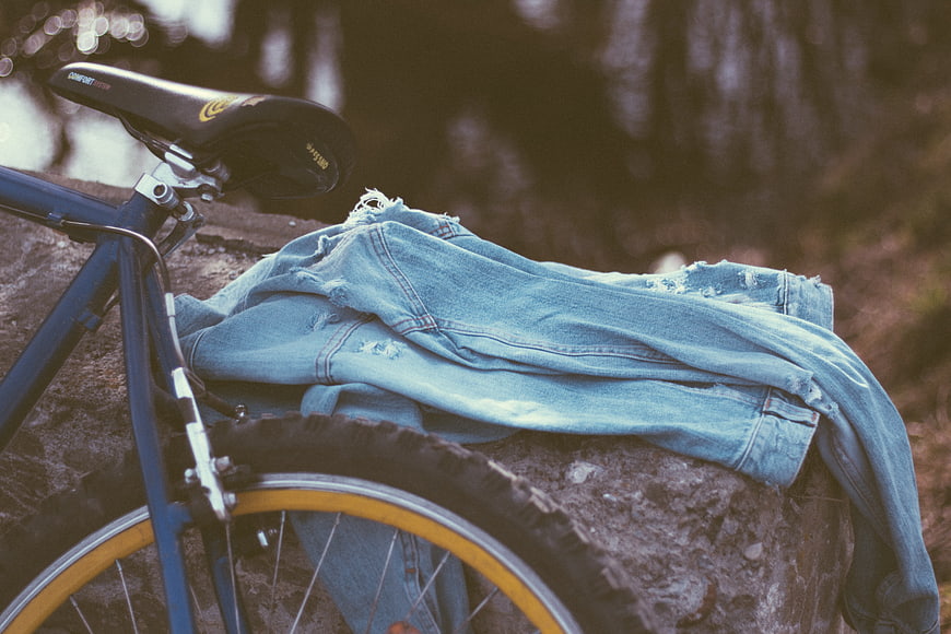 Vintage bicycle with denim jacket on rock in forest
