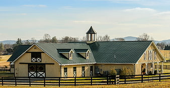 Rustic Yellow Horse Barn With Green Metal Roof And Cupola
