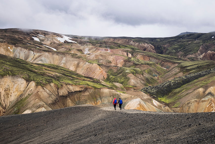 Hikers walking on volcanic landscape with colorful hills