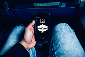 Man holding smartphone with motivational wallpaper on airplane