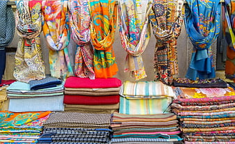 Colorful patterned scarves and textiles hanging in a market stall