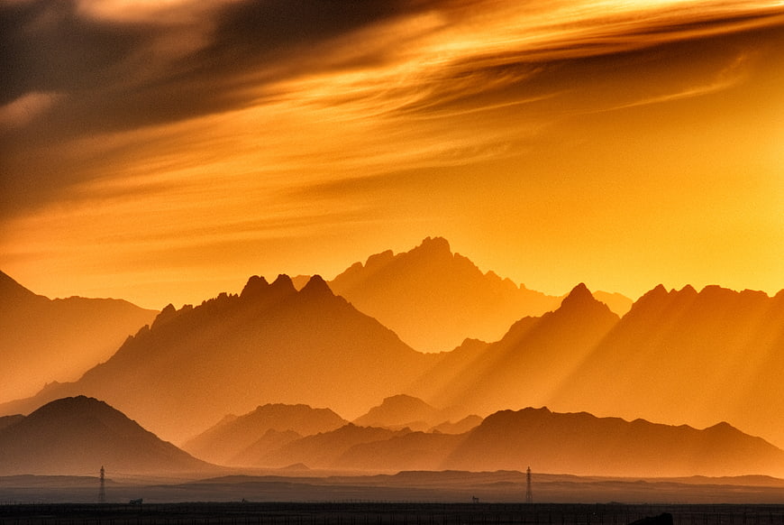 Golden Sunrise Over Layered Mountain Silhouettes