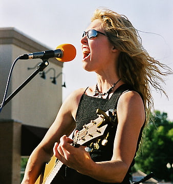 Blonde Female Rock Singer Performing with Guitar and Microphone