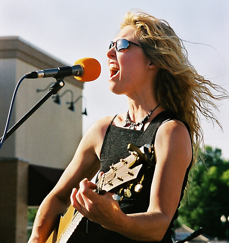 Blonde Female Rock Singer Performing with Guitar and Microphone
