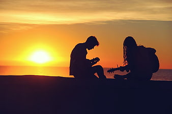 Silhouette of Couple Playing Guitars at Sunset on Beach