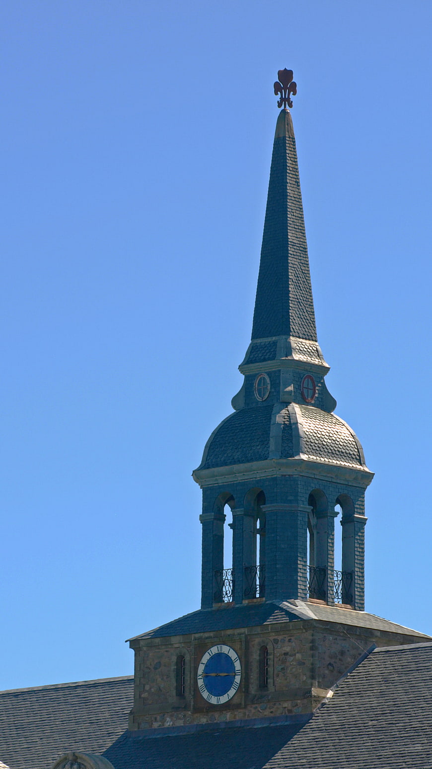 Historic church steeple with clock against blue sky