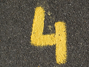 Yellow Number Four Painted On Dark Asphalt Road Surface