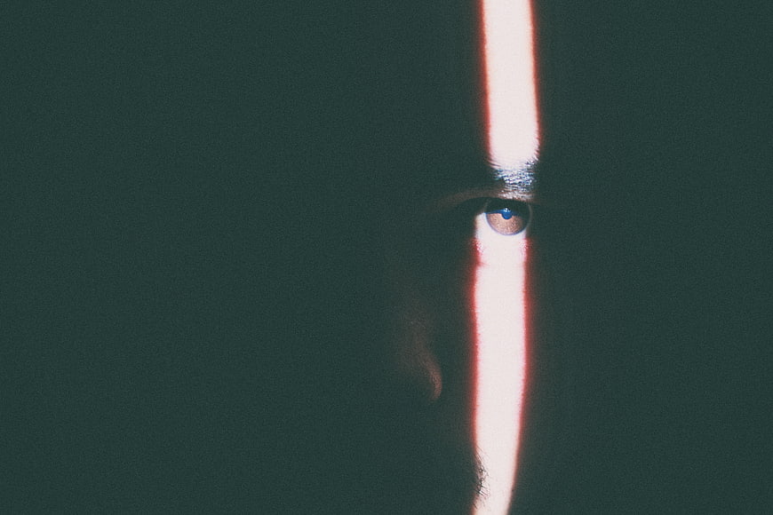 Close-up of man's eye illuminated by vertical light beam