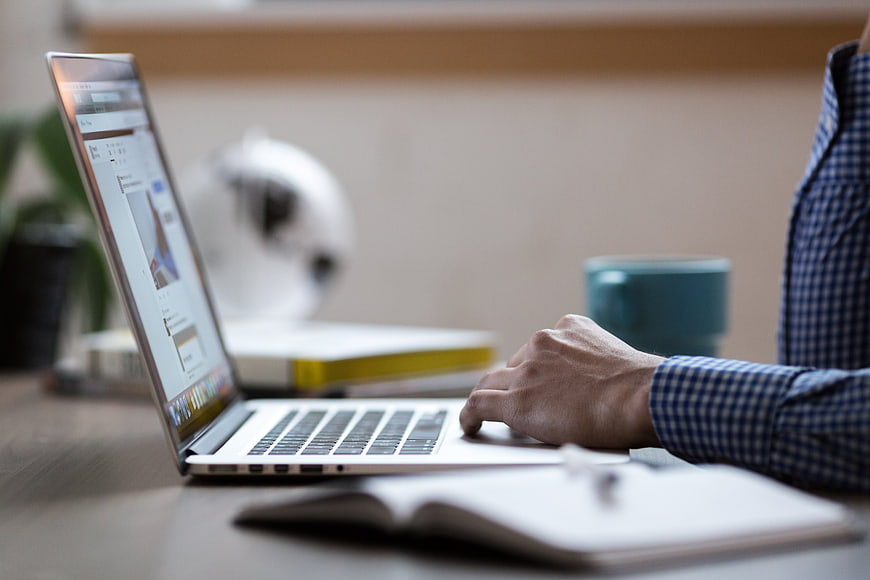 Man typing on laptop in modern office workspace