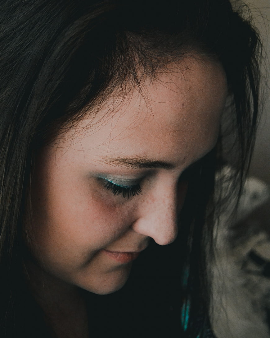 Close-up portrait of woman with teal eyeshadow looking down