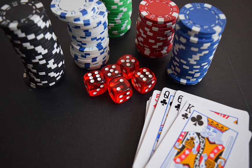 Poker chips, dice, and playing cards on black table