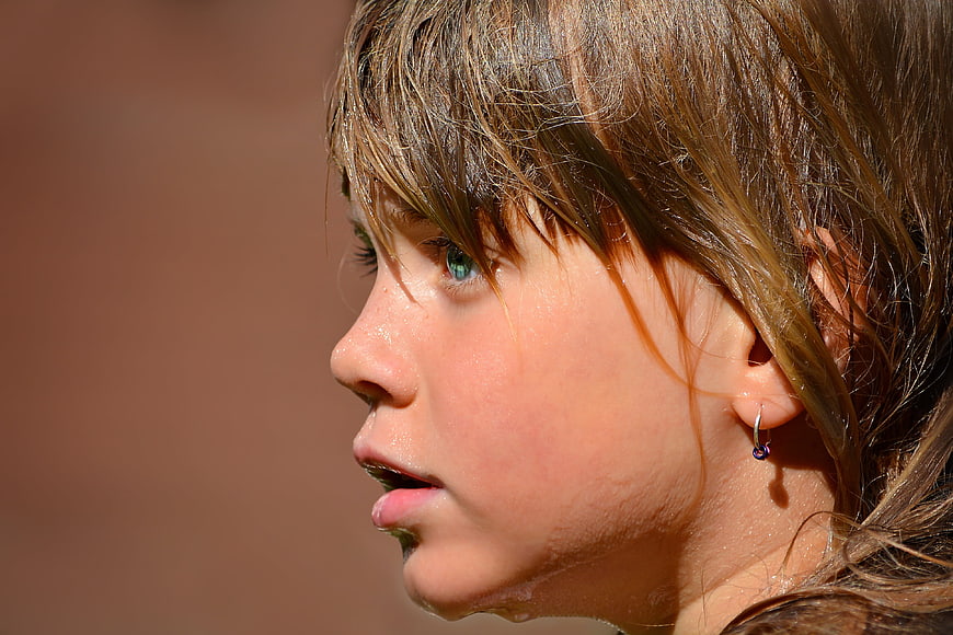 Close-up profile of a wet young girl's face in sunlight