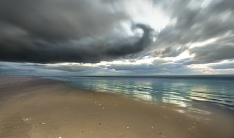 Dramatic storm clouds over calm ocean beach landscape