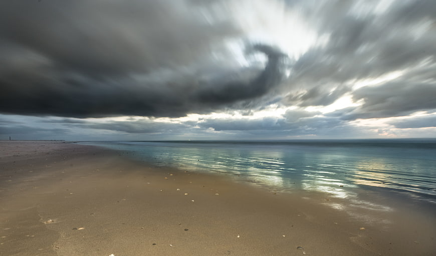 Dramatic storm clouds over calm ocean beach landscape