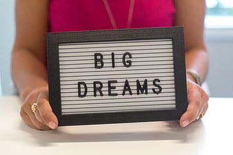 Woman holding letter board with big dreams quote
