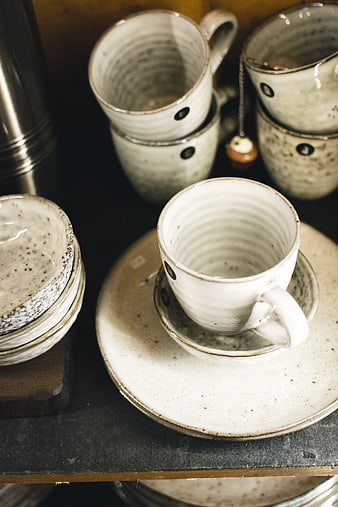 Stacked handmade ceramic tea cups on dark shelf