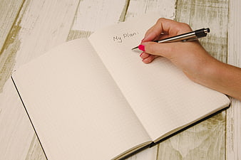 Hand writing My Plan in notebook on wooden table