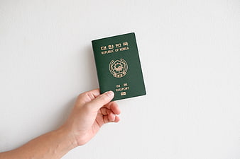 Hand holding Republic of Korea passport on white background