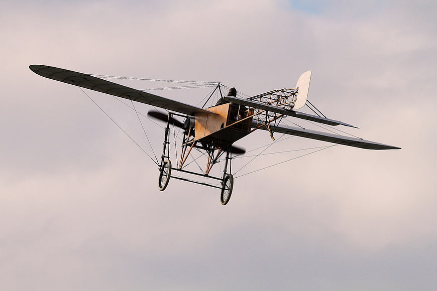 Vintage Biplane Flying Against Cloudy Sky