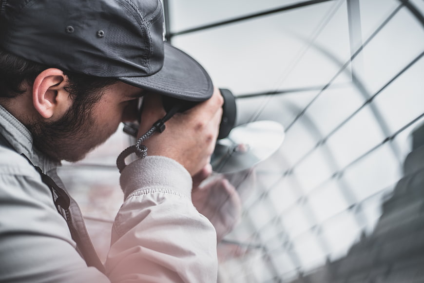 Man with Camera Looking Through Glass Roof