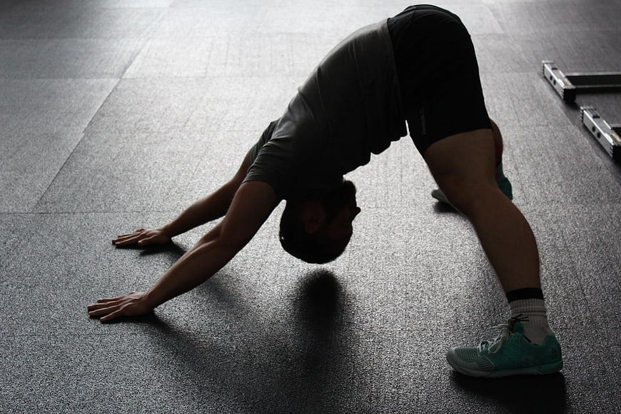 Man in Downward Dog Yoga Pose on Gym Floor