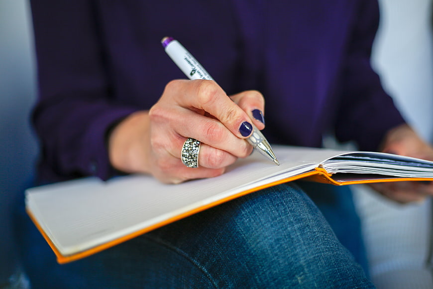 Woman Writing in Notebook with Pen