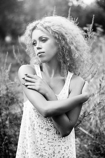 Black and white portrait of woman with curly hair in field