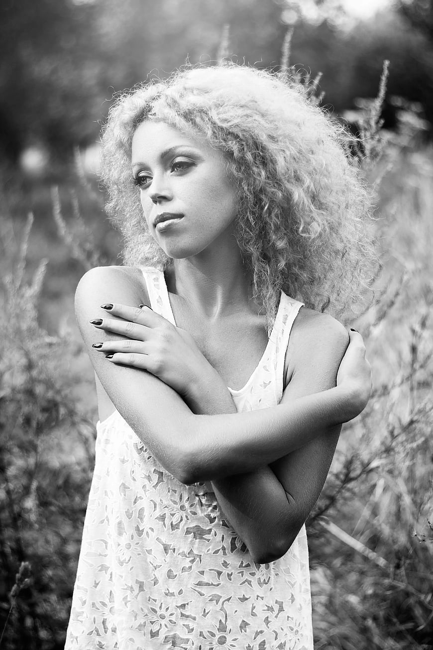 Black and white portrait of woman with curly hair in field