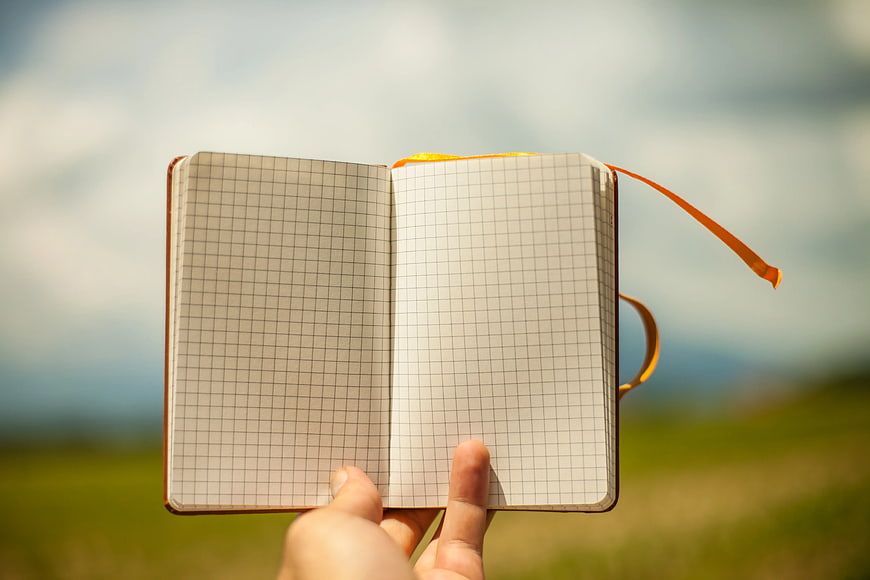 Hand Holding Open Graph Paper Notebook Outdoors