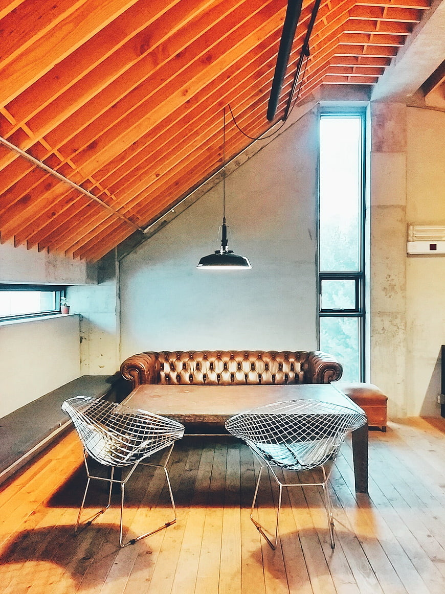 Industrial Loft Interior With Brown Leather Chesterfield Sofa And Wire Chairs