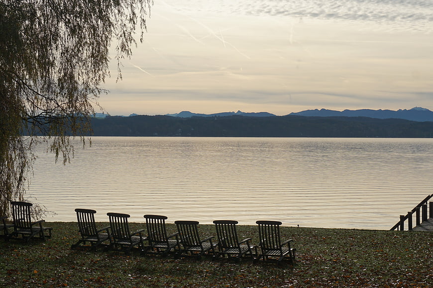Serene Lake View with Wooden Chairs and Distant Mountains