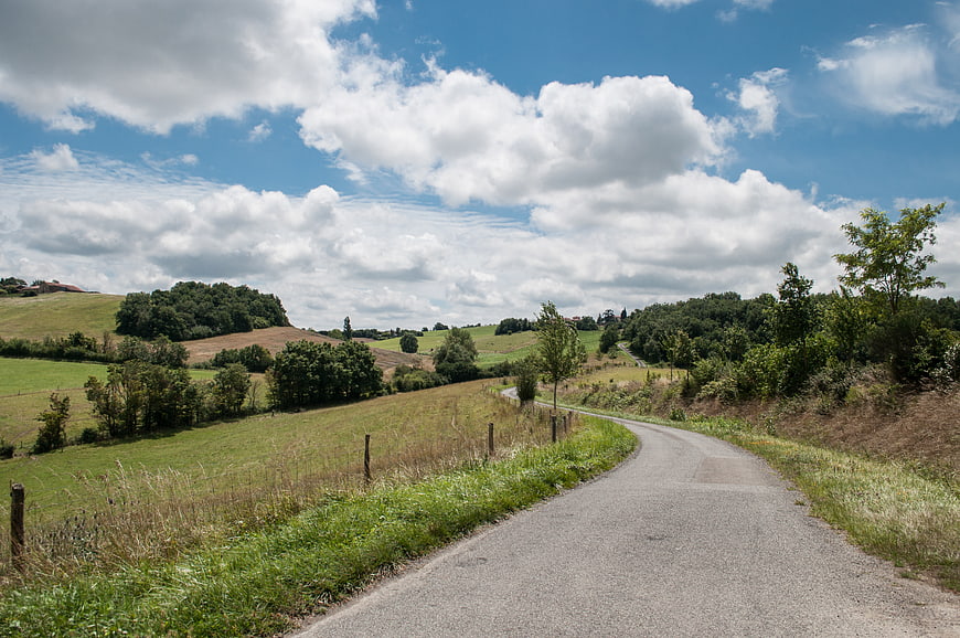 Winding country road through rolling green hills and blue sky