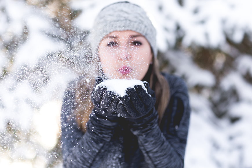 Woman Blowing Snow from Hands in Winter Forest