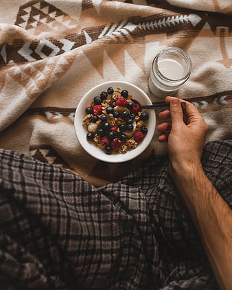 Healthy breakfast bowl with granola and berries in bed