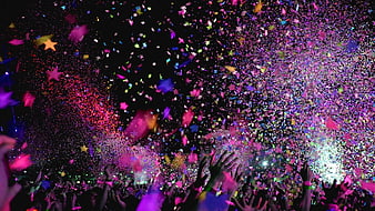 Vibrant confetti explosion over concert crowd at night