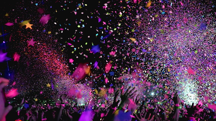 Vibrant confetti explosion over concert crowd at night