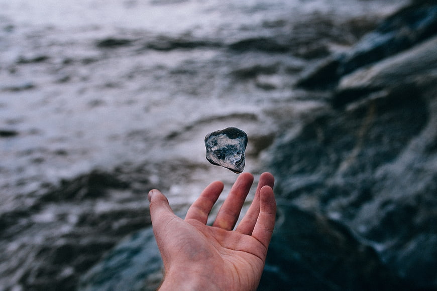 Hand Levitating Rock Over Ocean Waves