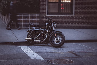 Black motorcycle parked on city street with brick building background